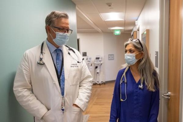 Photo of Dr. Mark Avdalovic, director of the Post-Covid-19 Clinic talking to colleague Namita Sood at a UC Davis Health facility.