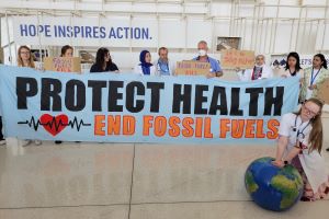 Group of demonstrators at COP28 with sign saying "Protect Health End Fossil Fuels"