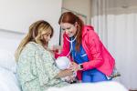 image of a mother in a hospital gown next to a hospital provider holding a baby