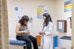 A physician in a doctor's office with a woman who is pregnant