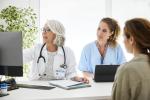 image of two health care professionals looking on a computer and talking to a patient