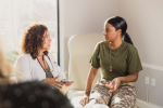 health care professional in white coat speaking with veterans patient in military fatigues