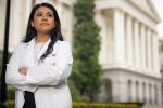Angelica Martin, wearing a white medical lab coat, poses for photo in front of the California state Capitol building in Sacramento