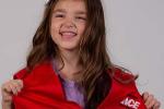 Pediatric patient poses with red Ace Hardware vest and nametag.