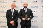 Neurosurgeon David Brandman is holding the Top 10 clinical research award and standing to the left of the chair of the Clinical Research Forum Harry Selker.