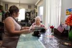 Latina caregiver sits at table with elderly mother for whom she cares