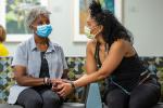 African American daughter comforting her mother in clinic waiting room