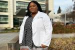 Portrait of medical student Chelsea Nash in white lab coat posing in front of a building at the UC Davis School of Medicine