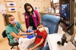 Child sitting in chair and nurse doing ultrasound on his right arm