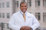 Doctor in white coat standing with hands folded