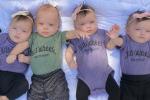 Four babies in matching outfits lying next to one another on a blanket
