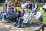 People sitting in chairs and standing looking at someone speak