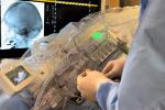 Surgeon working with robot machinery while seeing skull on screen