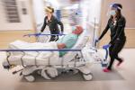 ED nurses run through hallway pushing patient on bed