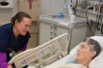 Physician at bedside smiling at older patient lying in emergency department