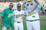 Two men in baseball jerseys standing next to costumed character.