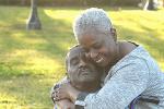 Black woman hugging husband in wheelchair