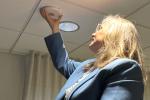 Professor Fritz with arm outstretched above her head placing white sensor on the ceiling