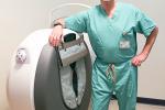 Man in scrubs leans against white circular machine