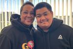 Woman with short hair and black sweatshirt stands next to young man with black sweatshirt.