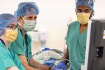 Surgeons wearing green scrubs in operating room look at a computer screen