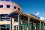 The exterior of the UC Davis MIND Institute, a large brown and glass building featuring a rotunda in the center. 