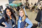 Veronica Encarnacion and Mallorie Mullendore wear blue scrubs and stand in front exercise machines