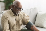 Active senior man measuring his blood pressure in living room