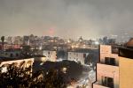 Rooftops of apartment homes with wildfire burning in the background
