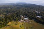 An aerial view of UC Santa Cruz, in the foreground among a forest, and the Pacific Ocean farther away