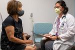 Nurse practitioner with white coat sitting and speaking with patient