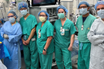 Five people posing in surgical room wearing green scrubs