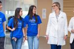 Three students and two instructors walk together while talking in hallway