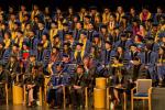 Group of people sitting on stage wearing caps and gowns