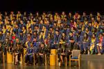 Students wearing blue graduation gowns on stage