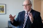 Stephen Cavanagh stands with hands outstretched as if talking to another person not seen in photo