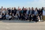 participants of bus trip pose shoulder to shoulder in front of oil rigs in Central Valley