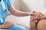 clinician with scrubs and stethoscope around neck holds hand of patient