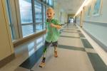 Boy with prosthetic legs runs in hospital corridor