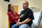 A doctor listens to her patient’s heartbeat with a stethoscope during a checkup in a medical exam room.