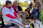 Six medical students provide foot care to three men at a picnic table after walking 15 miles during a march for farmworkers