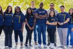 A diverse group of 12 medical students stand shoulder-to-shoulder wearing blue UC Davis t-shirts