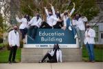 Medical students smiling and waving arms on sign
