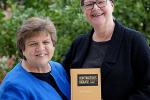 Two women holding book, showing cover of the book.