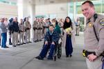Aaron Weikert is pushed in a wheelchair surrounded by CHP officers