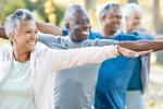 Older adults staggered in a line with outstretched arms doing exercise