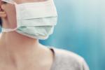 Woman wearing a grey sweater and mask over face