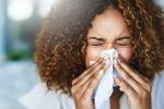 Woman sneezing into a tissue
