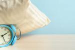 Blue alarm clock under a beige pillow.