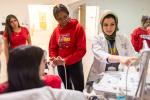 A student moves a device on the wrist of another student while a doctor points to a screen.